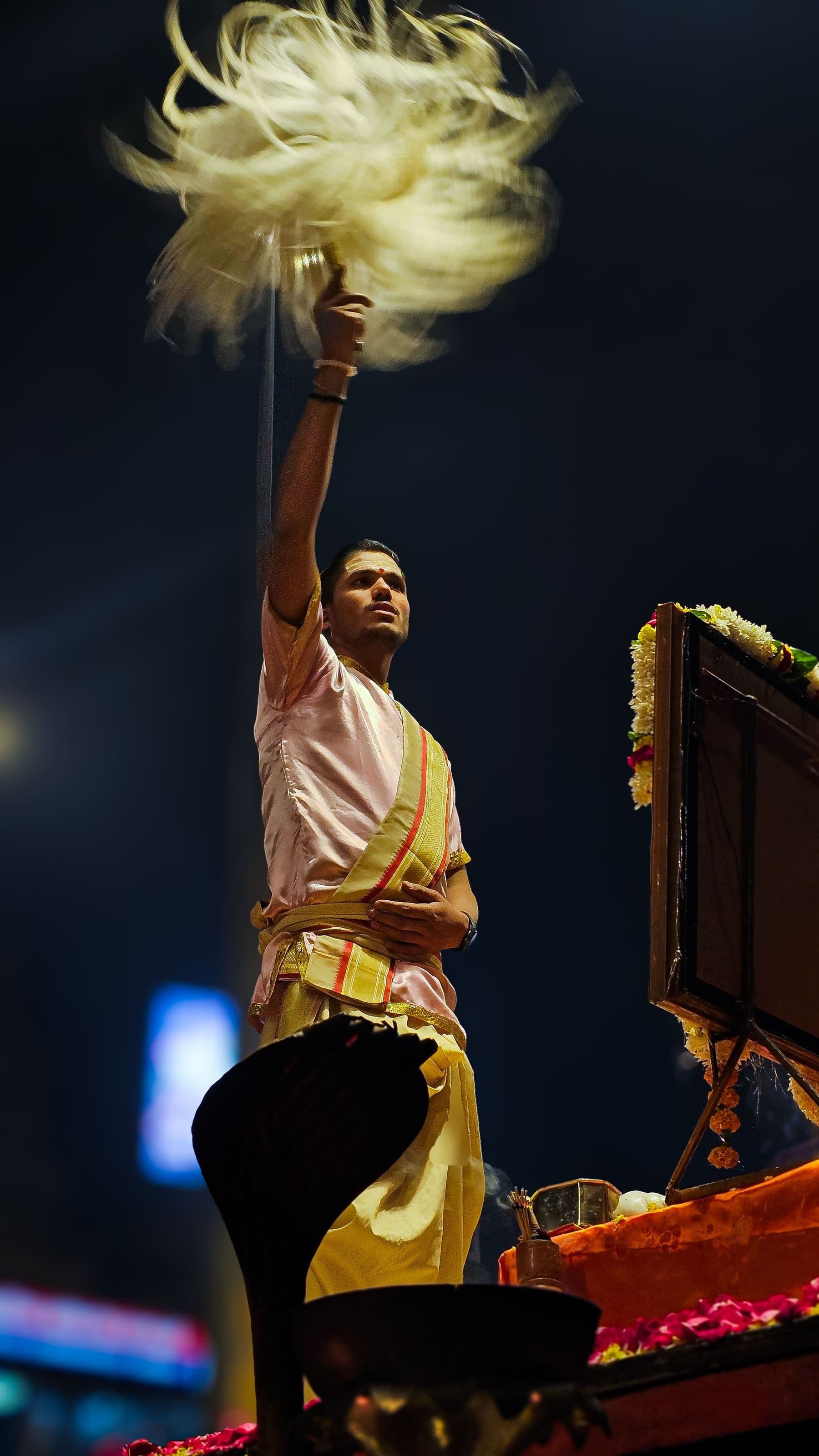 A priest raises the yak-tail whisk during the Ganga Aarti at night