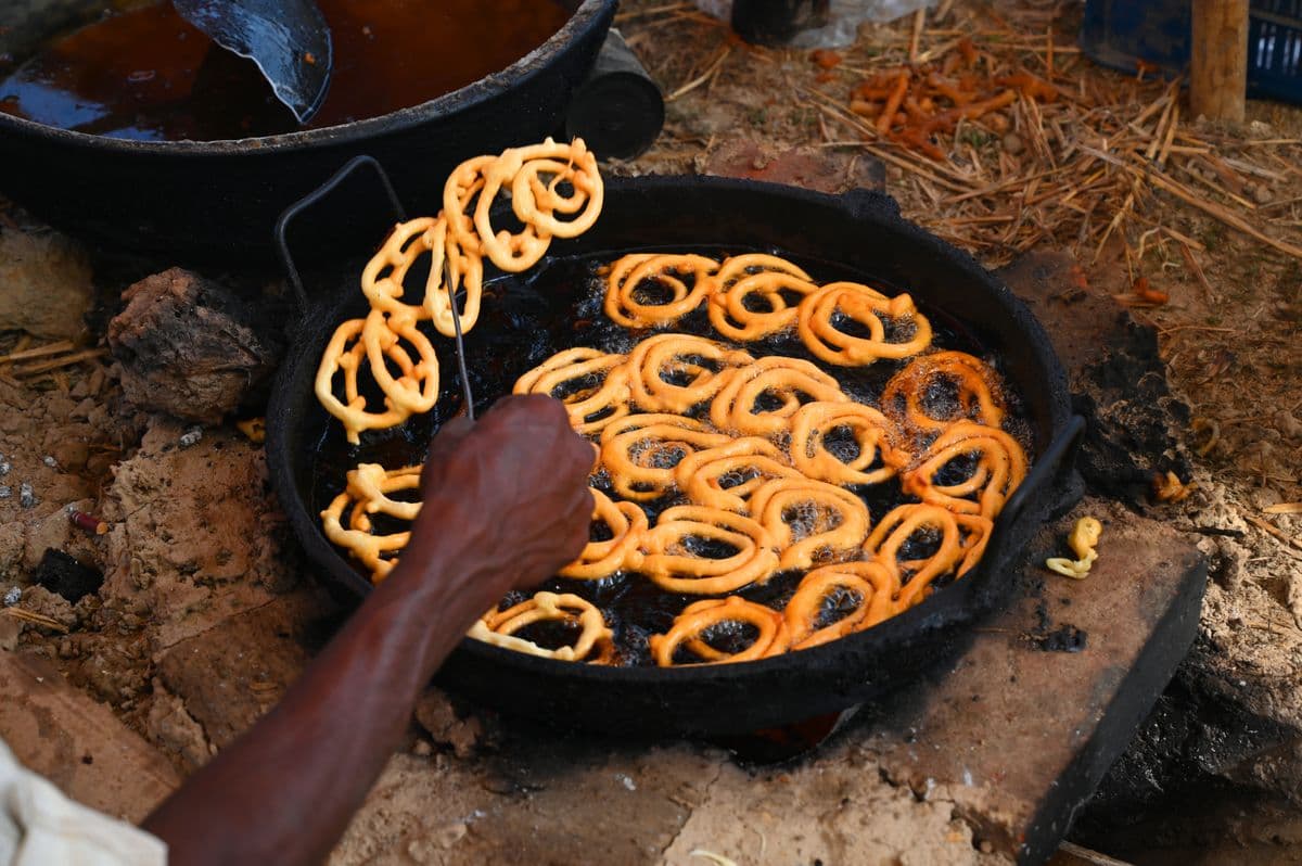 Jalebi frying in a wide iron pan