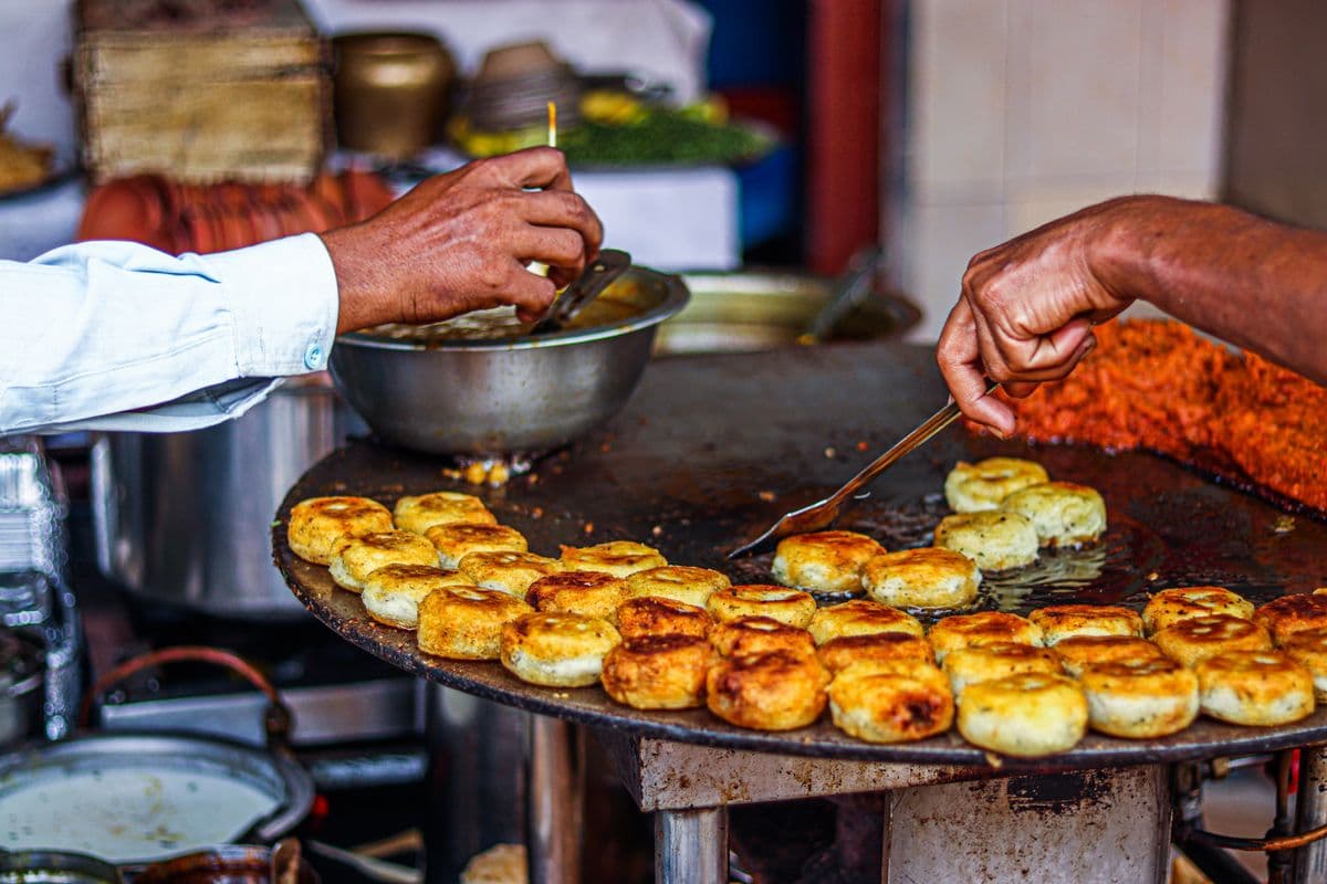 Aloo tikki crisping on a street-side tawa