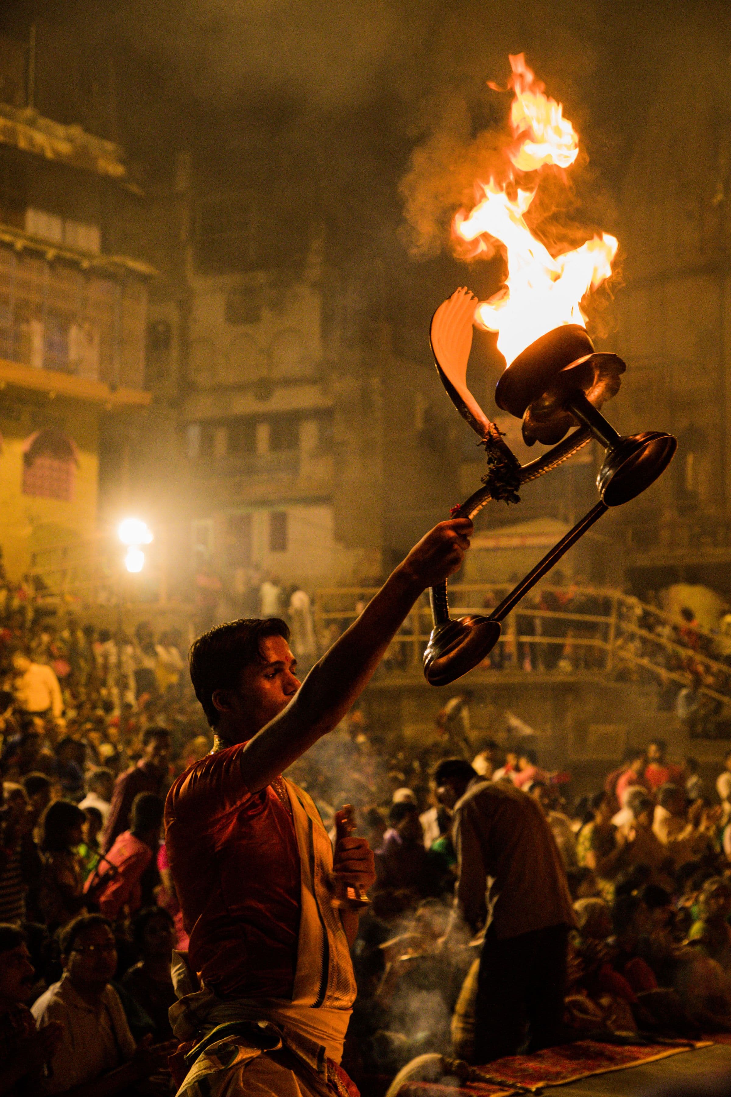 The Aarti flame raised above the crowd on the ghats at night